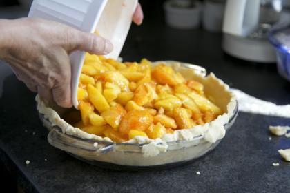 image of woman pouring apple pie filling into a pie plate