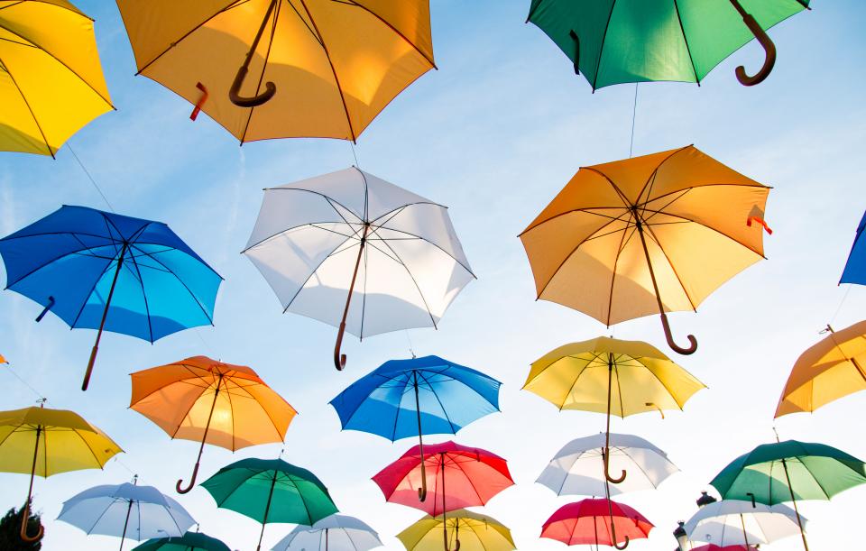 image of bright blue sky with various color umbrellas parachuting down