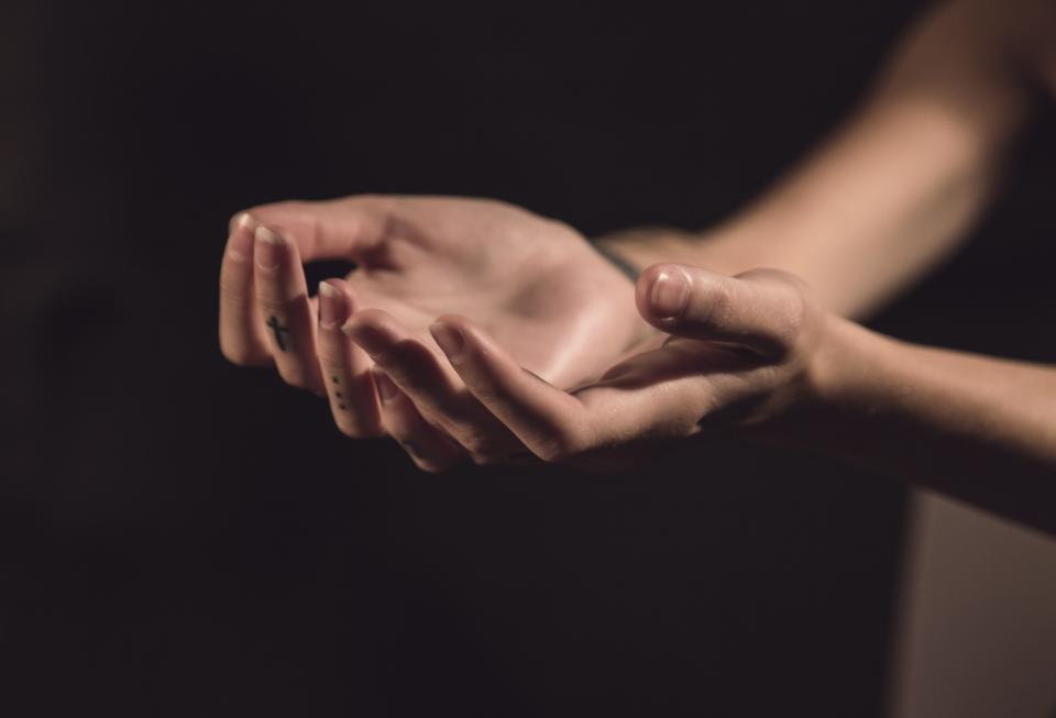 person's hands reaching out with dark background