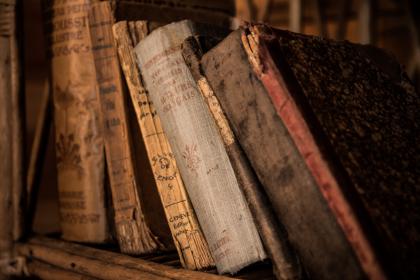 antique books upright on a bookshelf