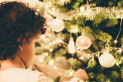 girl putting ornament on christmas tree